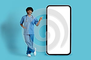 Happy indian doctor pointing at huge phone with white screen