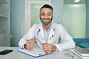 Happy Indian doctor talking to webcam consulting remote patient on video call.