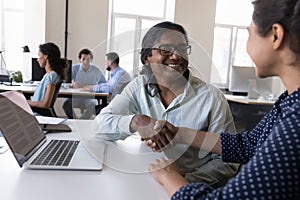 Happy Indian employees giving handshakes at shared workplace