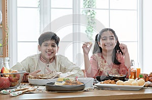 Happy Indian family enjoy eating food with hands, South Asian sibling, brother and sister smiling looking at camera