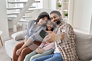 Happy indian family with teen daughter having fun take selfie on phone at home.