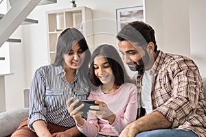 Happy indian family and teen daughter using smart phone at home.