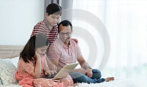 Happy indian family teenage boy son and girl with dad talking, teaching and doing daughter homework on laptop together at home