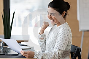 Happy indian female employee triumph reading good news in letter