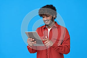 Happy indian guy using digital tablet isolated on blue background.