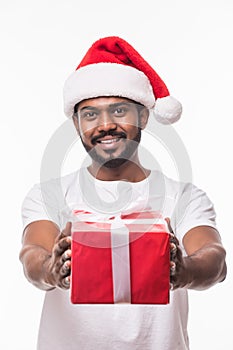 Happy indian handsome man wearing santa hat and holding gift box isolated on white background