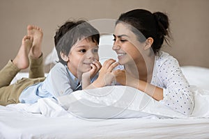 Happy Indian little boy and cheerful mom resting in bed