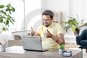 Happy indian man with laptop at home office