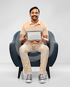 Happy indian man with tablet pc computer in chair