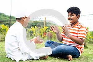 Happy indian multiethnic kids playing slapping and clapping hand game at park - concept of childhood outdoor activities,