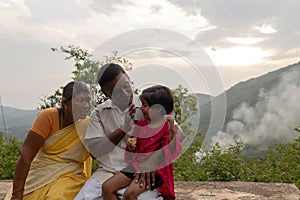 Happy Indian Retired Couple Enjoying Vacation with Granddaughter in a Picturesque Hill Station