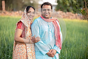 Happy indian rural farmer couple in agricultural field