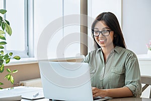 Happy indian young woman using laptop computer work study at home office.