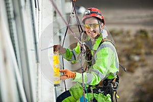 Happy industrial climber measuring with level tube during construction works