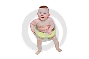 A happy infant baby bathes in water while sitting on a chair in a white t