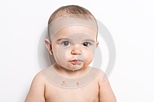 Happy infant baby boy doing a mess eating puree