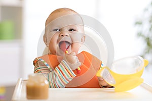Happy infant baby boy spoon eats itself photo