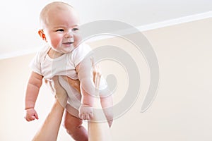 Happy infant baby girl being held up in the air