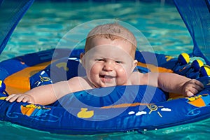 Happy infant playing in pool while sitting in baby float