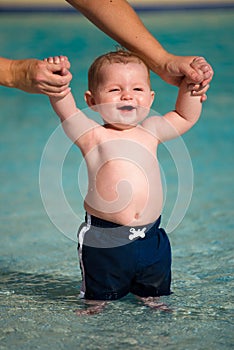 Happy infant playing and wading in shallow pool