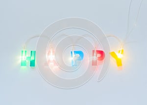 Happy inscription. Multicolored glowing letters on white matte background. Led volumetric lettering.