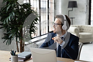 Happy inspired business professional in headphones listening to learning audio