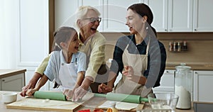 Happy intergenerational women gather together in kitchen to prepare cookies