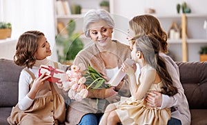 Happy International Mother's Day. daughter and granddaughter giving flowers to grandmother celebrate Women's Day