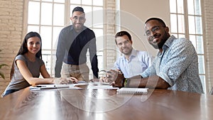 Happy international professional business team posing together at office table