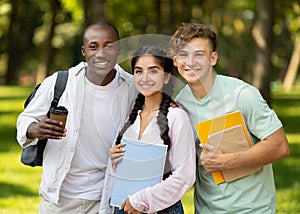 Happy international university students having break after classes and posing with notebooks outdoors in campus
