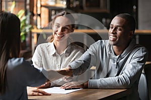 Happy interracial couple handshake bank manager take mortgage loan