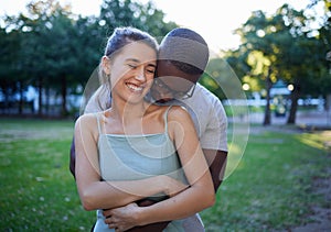 Happy interracial couple, hug and smile for romance, love or care or together in a nature park. Woman smiling with man