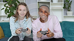 Happy interracial couple playing video games together at home