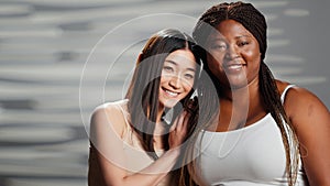 Happy interracial ladies laughing at camera and hugging