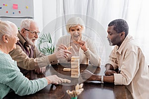 happy interracial pensioners playing tower wood