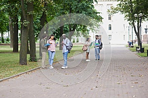 Happy interracial students with notebooks in a summer park.