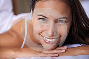 Happy that its finally weekend. Closeup portrait of a beautiful young woman lying on her bed.