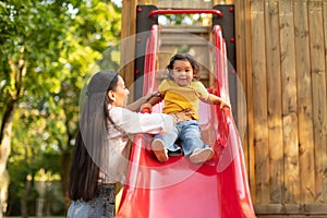 Happy Japanese Baby Daughter Enjoying Playground Playtime With Mom Outdoors