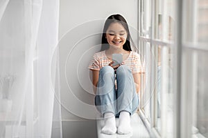 Happy japanese girl schooler playing games on cellphone, panorama