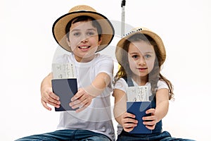 Happy journey! Family of travelers brother and sister with suitcase, air tickets and passports on white background