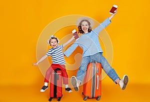 Happy journey! family of travelers mother and child  with suitcases tickets and passports on yellow background