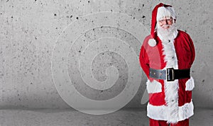 Happy jovial Santa Claus with copy space over a grey textured wall background to wish you a Merry Christmas photo