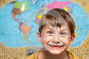 Happy and joyful boy on the background of the atlas of the world, a schoolboy studying science