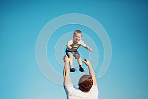 Happy joyful child, father fun throws up son in the air, summer