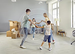 Happy joyful family dancing and having fun in their new spacious apartment on moving day