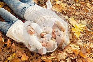 Happy joyful family portrait, mother and daughter have a rest laying on yellow maple leaves