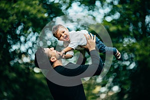 Happy joyful father having fun throws up in the air his small child