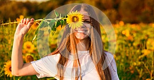 Happy joyful girl with sunflower enjoying nature and laughing on summer  field