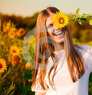 Happy joyful girl with sunflower enjoying nature and laughing on summer  field