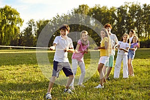 Happy joyful kids playing in tug-of-war with a rope in the summer park in nature in children camp.